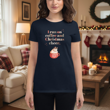 Load image into Gallery viewer, Person wearing a navy blue t-shirt with a Christmas-themed design in a festive living room.