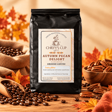 Load image into Gallery viewer, A black bag of Chiefy's Cup Coffee Co. Autumn Pecan Delight ground coffee stands on a wooden surface surrounded by coffee beans, pecans, burlap sacks, and autumn leaves.