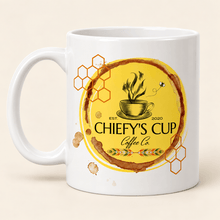 Load image into Gallery viewer, A white ceramic coffee mug featuring a circular yellow and brown graphic design with the text 'CHIEFY'S CUP Coffee Co' and honeycomb motifs, set against a light beige background.