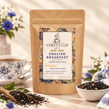 Load image into Gallery viewer, A stand-up kraft paper pouch of Chiefy's Cup Loose Leaf Tea labeled English Breakfast, styled on a tabletop with a blue floral teacup, loose tea in a spoon and bowl, flowers, and a soft neutral background.