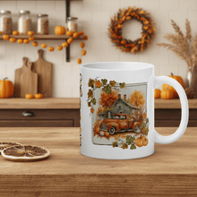 Load image into Gallery viewer, White mug with autumn-themed design featuring a truck and pumpkins on a wooden table.