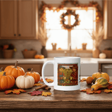 Load image into Gallery viewer, White mug with a colorful design on a kitchen counter with pumpkins and autumn decorations.