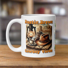 Load image into Gallery viewer, Left side view 11 oz white glossy mug with image phrase "Rustic Brews Cowboy Views," featuring a rustic cowboy hat resting on a weathered table, with a steaming cup of coffee and an old lantern beside it.