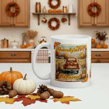 Load image into Gallery viewer, White mug with 'Thankful & Blessed' design in a kitchen setting with pumpkins and autumn decorations.