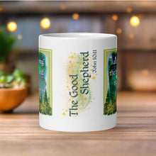 Load image into Gallery viewer, Back side view of a white glossy mug featuring the phrase "The Good Shepherd" with the Bible verse John 10:11, surrounded by golden sparkles and a soft background.
