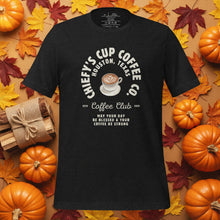 Load image into Gallery viewer, Black t-shirt with coffee-themed design on a background of pumpkins and autumn leaves