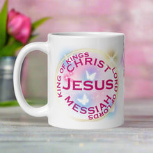 Load image into Gallery viewer, Left side view white glossy mug with image phrase "King of Kings, Lord of Lords, Messiah, Christ, Jesus," with image design of translucent butterflies, golden translucent circle surrounding the image phrase, golden and pink bright sparkles, with light pink and blue hues in the background.