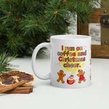 Load image into Gallery viewer, Left side view of a white glossy mug with the phrase "I run on coffee and Christmas cheer" in festive font, featuring a Christmas mug topped with whipped cream, gingerbread men and women, with sparkles and a yellow mist in the background.