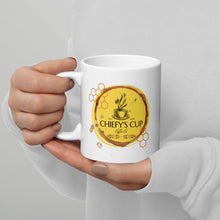 Load image into Gallery viewer, A person in a white long-sleeve top holds a white ceramic mug with a yellow and brown honey-themed graphic that reads 'CHIEFY'S CUP Coffee Co'.