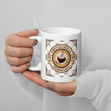Load image into Gallery viewer, A person in a white long-sleeve top holds a white ceramic mug featuring a circular coffee-themed graphic with the text 'Chiefy's Cup Coffee Co' and 'Premium Coffee' in brown and gold tones.