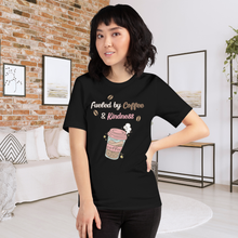 Load image into Gallery viewer, Woman wearing a black t-shirt with &#39;Fueled by Coffee &amp; Kindness&#39; design in a living room.
