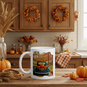 White mug with 'Fall Harvest' design in a kitchen setting with pumpkins and wreaths.