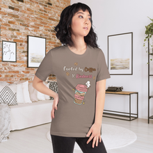 Load image into Gallery viewer, Woman wearing a brown t-shirt with a graphic design in a room with a brick wall and white couch.
