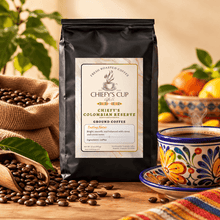 Load image into Gallery viewer, A black bag of Chiefy's Cup Coffee Colombian Reserve Ground Coffee stands on a wooden table surrounded by coffee beans, a colorful cup, and fruit in a warm, rustic setting.
