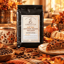 Load image into Gallery viewer, A black bag of Chiefy's Cup Coffee 'Autumn Pecan Delight' ground coffee stands on a rustic wooden table surrounded by autumn-themed props, including a cup of coffee, pecans, cinnamon sticks, a slice of pecan pie, and fall leaves.
