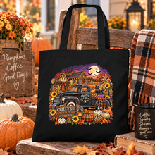 Load image into Gallery viewer, A black tote bag with a colorful autumn-themed graphic print featuring a vintage truck, pumpkins, sunflowers, and a Rustic barn in the background, displayed on a wooden bench in a cozy fall yard setting.
