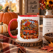 Load image into Gallery viewer, A white ceramic mug with a red handle and red interior, featuring a colorful autumn-themed graphic of an orange pickup truck in front of a cabin surrounded by fall foliage. The mug is styled on a rustic wooden table with pumpkins, a plaid blanket, coffee beans, and a 'Hello Fall' sign in the background.

