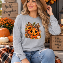 Load image into Gallery viewer, A woman wearing a light gray long-sleeve crewneck sweatshirt with a large autumn graphic on the front. The graphic features a smiling jack-o'-lantern, sunflowers, leopard print bows, and pumpkins.
