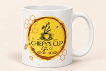 Load image into Gallery viewer, A white ceramic coffee mug featuring a circular yellow and brown graphic design with the text 'CHIEFY'S CUP Coffee Co' and honeycomb motifs, set against a light beige background.
