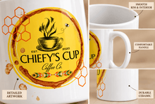 Load image into Gallery viewer, Image details of a white ceramic coffee mug featuring a circular yellow and brown graphic design with the text 'CHIEFY'S CUP Coffee Co' and honeycomb motifs, set against a light beige background.
