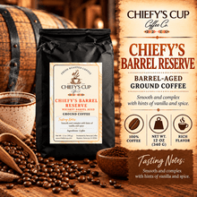 Load image into Gallery viewer, A bag of Chiefy's Cup Coffee Co. Chiefy's Barrel Reserve barrel-aged ground coffee stands on a wooden surface with coffee beans, a spoon, and a small bowl around it.
