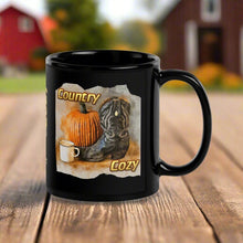 Load image into Gallery viewer, Right side view of a black glossy mug featuring the phrase &quot;Country Cozy&quot; with a design of a black cowboy boot beside a pumpkin and a steaming cup of coffee, with a rustic background.
