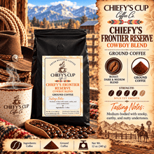 Load image into Gallery viewer, A bag of Chiefy's Cup Coffee Co. Chiefy's Frontier Reserve Cowboy Blend ground coffee is shown in a styled western-themed scene with a coffee mug, wooden spoon of coffee beans, cowboy hat, and mountain backdrop.
