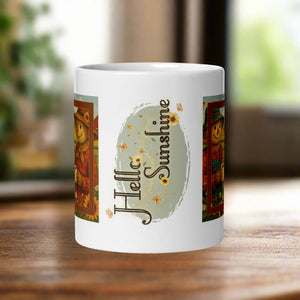 Back side view of a white glossy mug featuring the words "Hello Sunshine" with yellow sunflowers, butterflies, and blowing leaves surrounding a pastel green oval background.