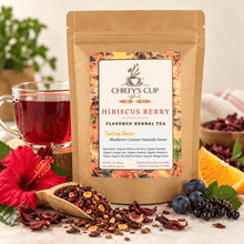 Load image into Gallery viewer, A kraft paper pouch of Chiefy's Cup  Hibiscus Berry Flavored Herbal Tea stands on a light surface, surrounded by loose dried hibiscus petals, a glass of red tea, a red hibiscus flower, blueberries, blackberries, and orange slices.
