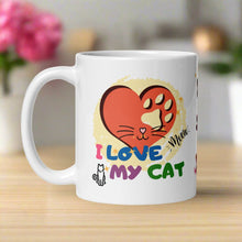 Load image into Gallery viewer, Left side view of a white glossy mug with a red heart design featuring a cat nose and whiskers in the center. Behind the heart is a faded yellow circle. The words “I love my cat” are displayed, along with a tiny cat outline and the playful word “meow.”
