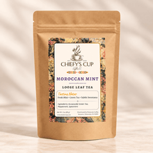Load image into Gallery viewer, A stand-up kraft paper pouch of Chiefy's Cup Coffee Co. Moroccan Mint loose leaf tea, featuring a floral label with purple text, set against a warm beige background with soft shadows.
