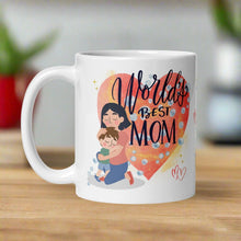 Load image into Gallery viewer, Left side view white glossy mug featuring a heartwarming illustration of a mother hugging a small boy, with a large watercolor heart in the background. Golden sparkles and soft bubbles surround the scene, with the words &quot;World&#39;s Best Mom&quot; above them.
