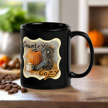 Load image into Gallery viewer, Right side view of a black glossy mug featuring the phrase &quot;Country Cozy&quot; with a design of a black cowboy boot beside a pumpkin and a steaming cup of coffee, with a rustic background.
