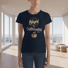 Load image into Gallery viewer, Front view of a woman wearing a navy blue “Blessed &amp; Caffeinated” t-shirt with golden script and a coffee bean design. The mockup is set in a bright modern space.
