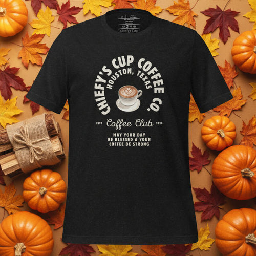 Black t-shirt with coffee-themed design on a background of pumpkins and autumn leaves
