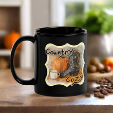 Load image into Gallery viewer, Left side view of a black glossy mug featuring the phrase &quot;Country Cozy&quot; with a design of a black cowboy boot beside a pumpkin and a steaming cup of coffee, with a rustic background.
