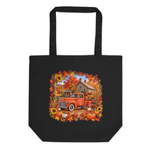 Load image into Gallery viewer, A black canvas tote bag with a colorful autumn-themed graphic print featuring an orange vintage pickup truck, pumpkins, sunflowers, and fall leaves, shown against a plain white background.
