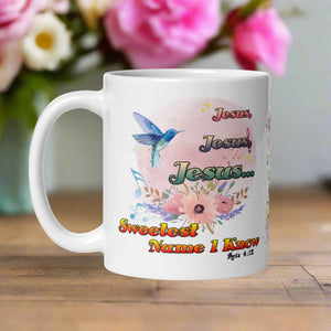 Left side view white glossy mug featuring the phrase "Jesus, Jesus, Jesus, Sweetest Name I Know" with a pastel floral arrangement, a blue mockingbird, swaying musical notes, and a light pink hue circle background with a Bible verse.