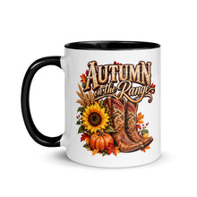 Load image into Gallery viewer, A white ceramic mug with a black handle and black interior, featuring a western autumn graphic that reads 'Autumn on the Range' with a cowboy boot, sunflower, pumpkins, and fall leaves.
