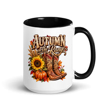Load image into Gallery viewer, A white ceramic mug with a black interior and handle, featuring a western-themed autumn graphic with the text 'AUTUMN on the Range' above cowboy boots, pumpkins, sunflowers, and fall leaves.
