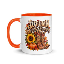 Load image into Gallery viewer, A white ceramic coffee mug with a bright orange handle and interior, featuring a western-themed autumn graphic with the text 'Autumn on the Range' above cowboy boots, pumpkins, sunflowers, and fall leaves.
