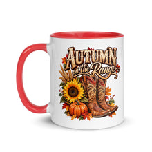 Load image into Gallery viewer, A white ceramic mug with a red handle and red interior, featuring a fall-themed graphic that reads 'Autumn on the Range' with cowboy boots, sunflowers, pumpkins, and autumn leaves.
