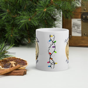 Back side view of a white glossy mug featuring a string of Christmas lights, a trail of kitten pawprints, and small colorful sparkles.