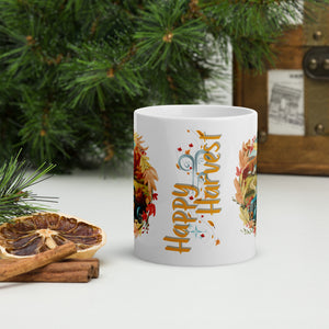 Back side view of a white glossy mug featuring the phrase "Happy Harvest" surrounded by windblown leaves and soft blue sparkles.