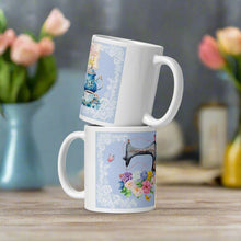 Load image into Gallery viewer, White glossy mug featuring a vintage coffee pot with a cup and saucer on the right, and a vintage sewing machine adorned with a bouquet of flowers and butterflies on the left. Both designs are set against a light blue background framed with delicate lace details, showcasing a charming and elegant theme.
