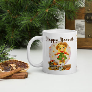 Left side view of a white ceramic mug featuring the phrase "Happy Harvest" with a design of a cute scarecrow behind a barrel of hay and small pumpkins, surrounded by falling leaves, small sunflowers, and pumpkins on a round yellow and purplish circle background.
