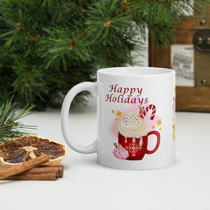 Left side view of a white glossy mug featuring the phrase "Happy Holidays" with a festive red mug design, topped with whipped cream, candy cane, cinnamon sticks, sprinkles, and golden sparkles, set against a pink-hued background.