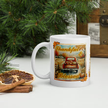 Load image into Gallery viewer, Left side view  of a white glossy mug with the phrase &quot;Thankful and Blessed&quot; in festive font, featuring an image of an old truck on a country road with a bed full of pumpkins on a late autumn day with a festive frame.
