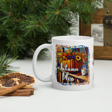 Load image into Gallery viewer, Left side view of white glossy mug with image phrase &quot;Autumn Bliss&quot; in festive font, featuring a vibrant fall-colored design of a pumpkin on a farm porch next to a hot drink, with a vibrant flower arrangement on top of the pumpkin, surrounded by a colorful frame.
