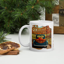 Load image into Gallery viewer, Left side view of a white glossy mug featuring the festive phrase &quot;Fall Harvest&quot; with a design of an old blue truck on a country dirt road, its bed filled with pumpkins and fall leaves, set against a backdrop of autumn-colored trees.
